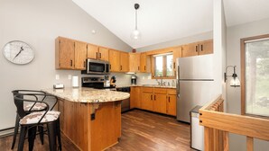 Una cocina moderna con armarios de madera, una isla central, un microondas y un refrigerador.