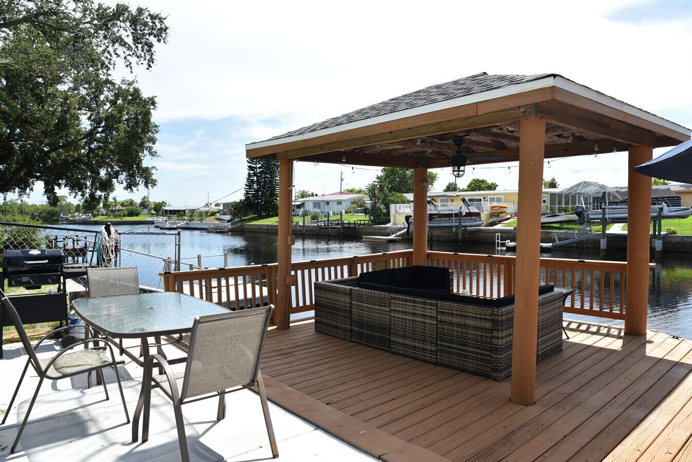 Eine überdachte Terrasse im Freien mit Grill, Sitzgelegenheiten und einem Whirlpool.
