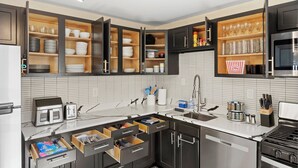 Eine moderne Küche mit offenen Schränken, einem eingebauten Backofen und einer Spüle aus Edelstahl.