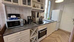 A kitchen with a microwave, coffee maker, and a sink. There are cabinets above the counter and a window with a view.