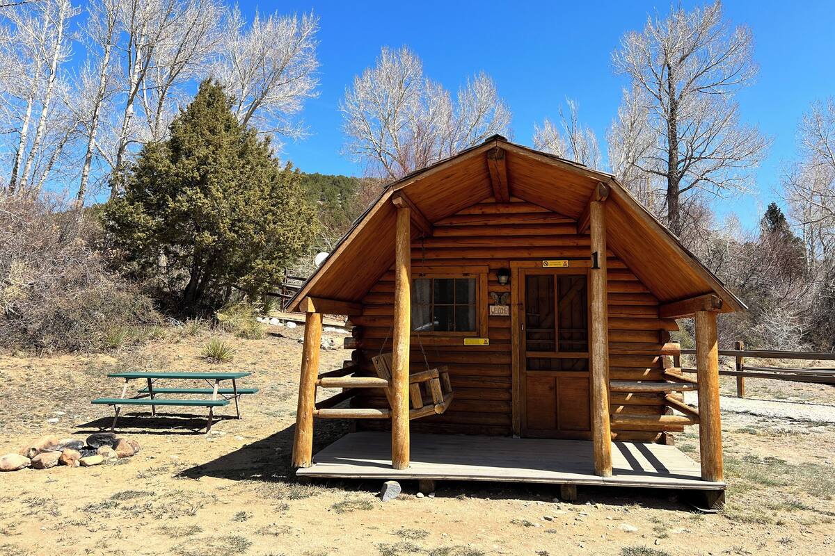 A wooden cabin with a porch, a bench, and a sign indicating it is a lodge.