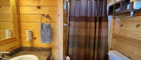 Un baño de madera con lavamanos, inodoro y cortina de ducha.