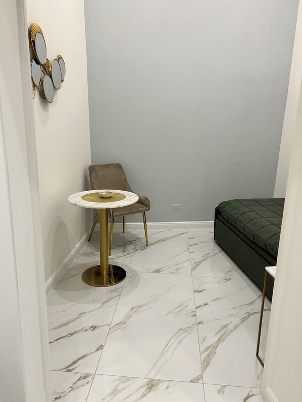 Une petite pièce moderne, dotée d’une table ronde, d’une seule chaise, d’un lit et d’un miroir fixé au mur.