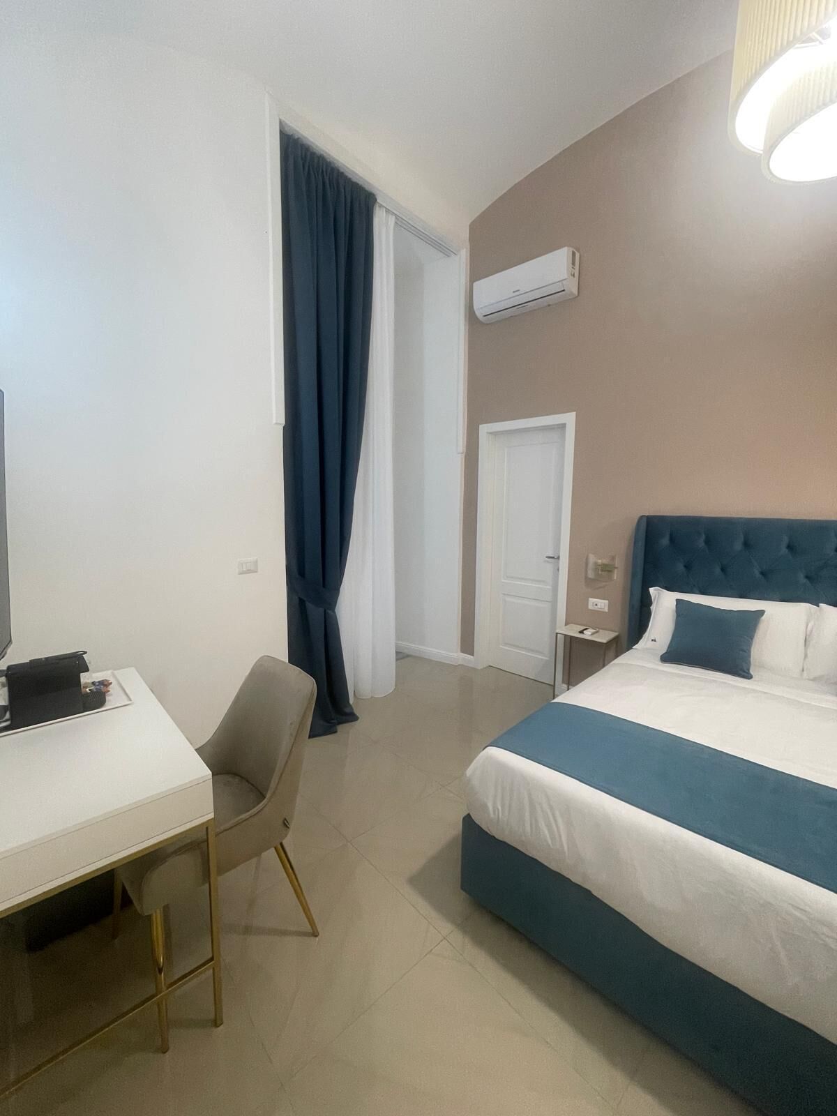 Una habitación de hotel con una cama, un escritorio, una silla y un equipo de aire acondicionado.