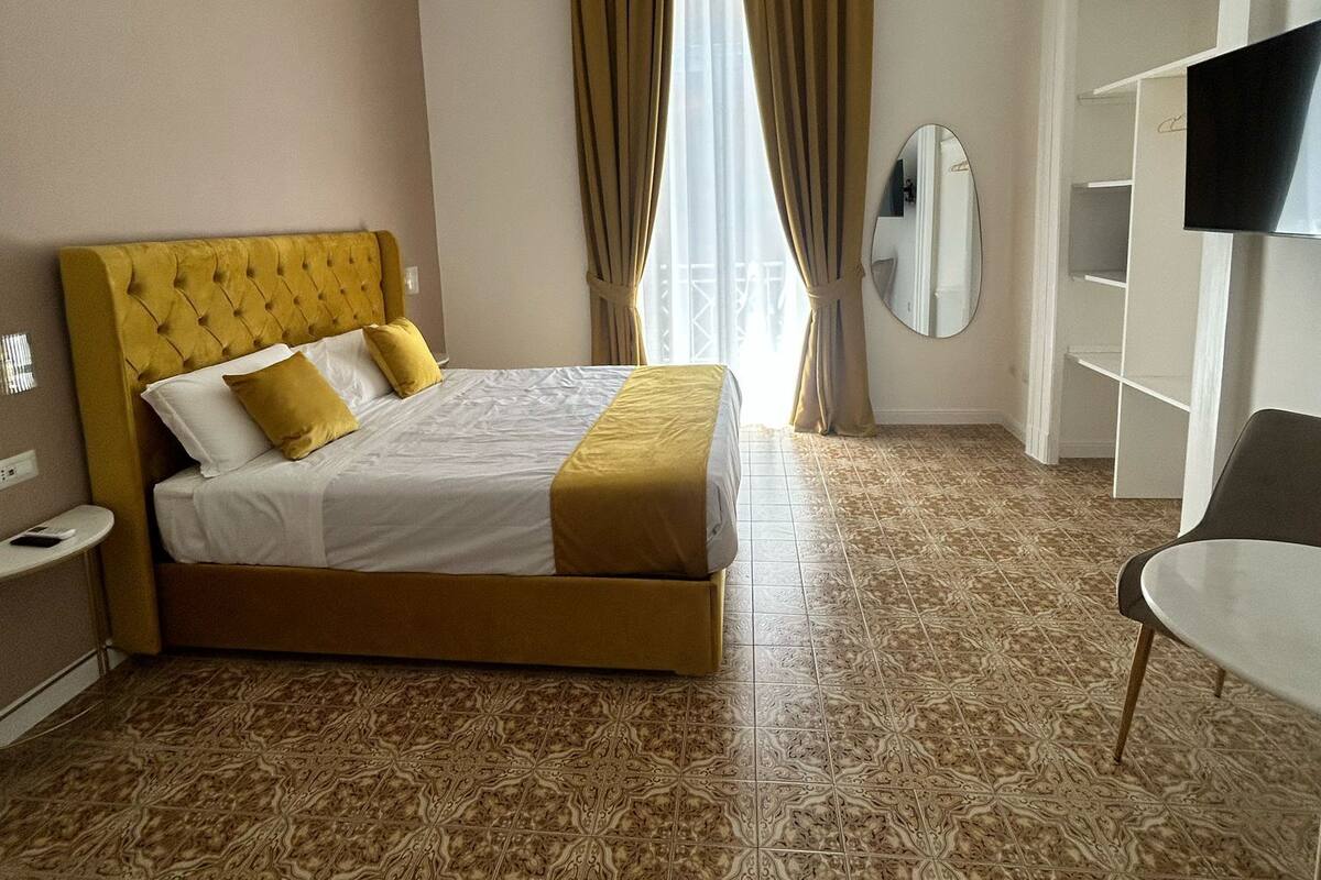 A hotel room with a bed, a chair, a TV, and a mirror.