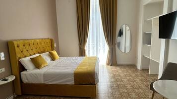 A hotel room with a bed, a chair, a TV, and a mirror.