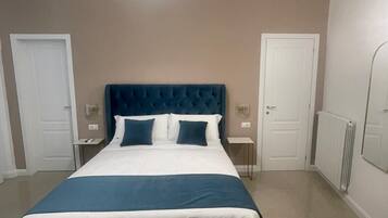 Un dormitorio con una cama grande, dos mesitas de noche, un aire acondicionado instalado en la pared y una lámpara en el techo.