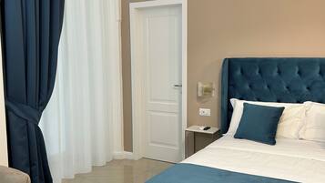 A hotel room with a bed, a bedside table, a nightstand, a wall-mounted air conditioner, and a door.
