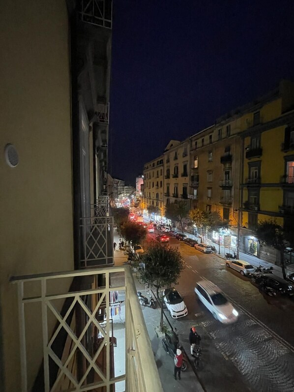 Une vue nocturne d’une rue de la ville, prise depuis un balcon.