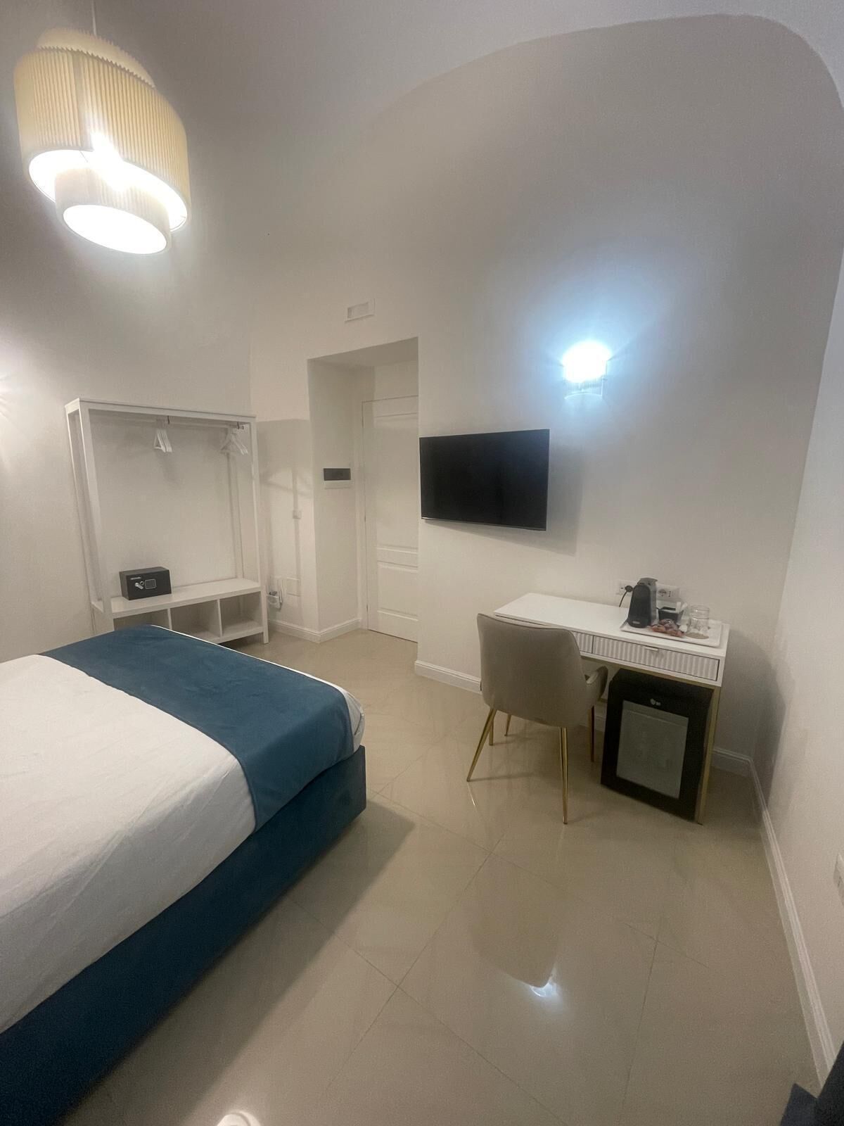 Habitació d'hotel amb llit, escriptori, televisió i armari.