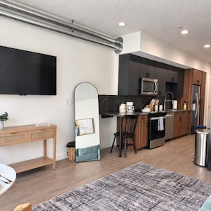 A modern kitchen with a flat-screen TV, a microwave, and a refrigerator.