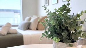 Un coin repas avec une table dressée pour deux personnes, une plante en pot et une bougie décorative.