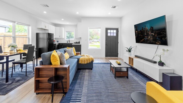 A modern living room with a sofa, coffee table, and a cityscape painting on the wall. - Cozy & Modern 3BR Houston Townhome - WiFi + AC (Houston)