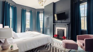 Un dormitorio moderno con una cama grande, una chimenea y un televisor montado en la pared.