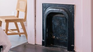 Una habitación con chimenea, una obra de arte enmarcada y un espejo decorativo.