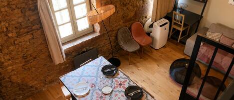 A dining area with a table set for four, a chair, a small heater, and a window with curtains.