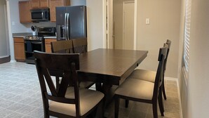Una cocina moderna con armarios de madera, electrodomésticos de acero inoxidable y un comedor con una mesa y sillas de madera oscura.
