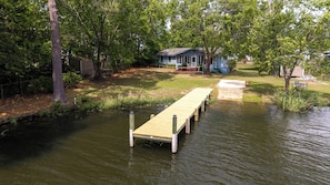 A wooden dock extending into a body of water, surrounded by trees and a house in the background. - Lakefront 3-bedroom home with private dock and ramp on Lake Marion, Manning, SC (Manning)