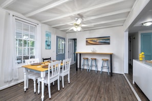 A dining area with a wooden table and white chairs, a ceiling fan, and a painting on the wall. - Lakefront 3-bedroom home with private dock and ramp on Lake Marion, Manning, SC (Manning)