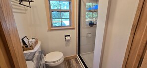 A small bathroom with a toilet, a window, and a shower area. - Relaxing Deep Creek Escape w/ Hot Tub (Oakland)
