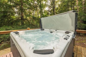 Un jacuzzi en una terraza de madera rodeado de un bosque.