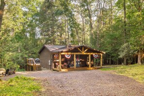 Una cabaña rústica con porche, rodeada de un bosque.