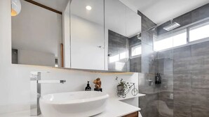 Une salle de bain moderne avec un grand lavabo blanc, un miroir et une cabine de douche en verre.