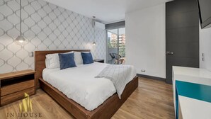 Une chambre à coucher moderne avec un lit en bois, du linge de lit blanc et un papier peint à motifs.