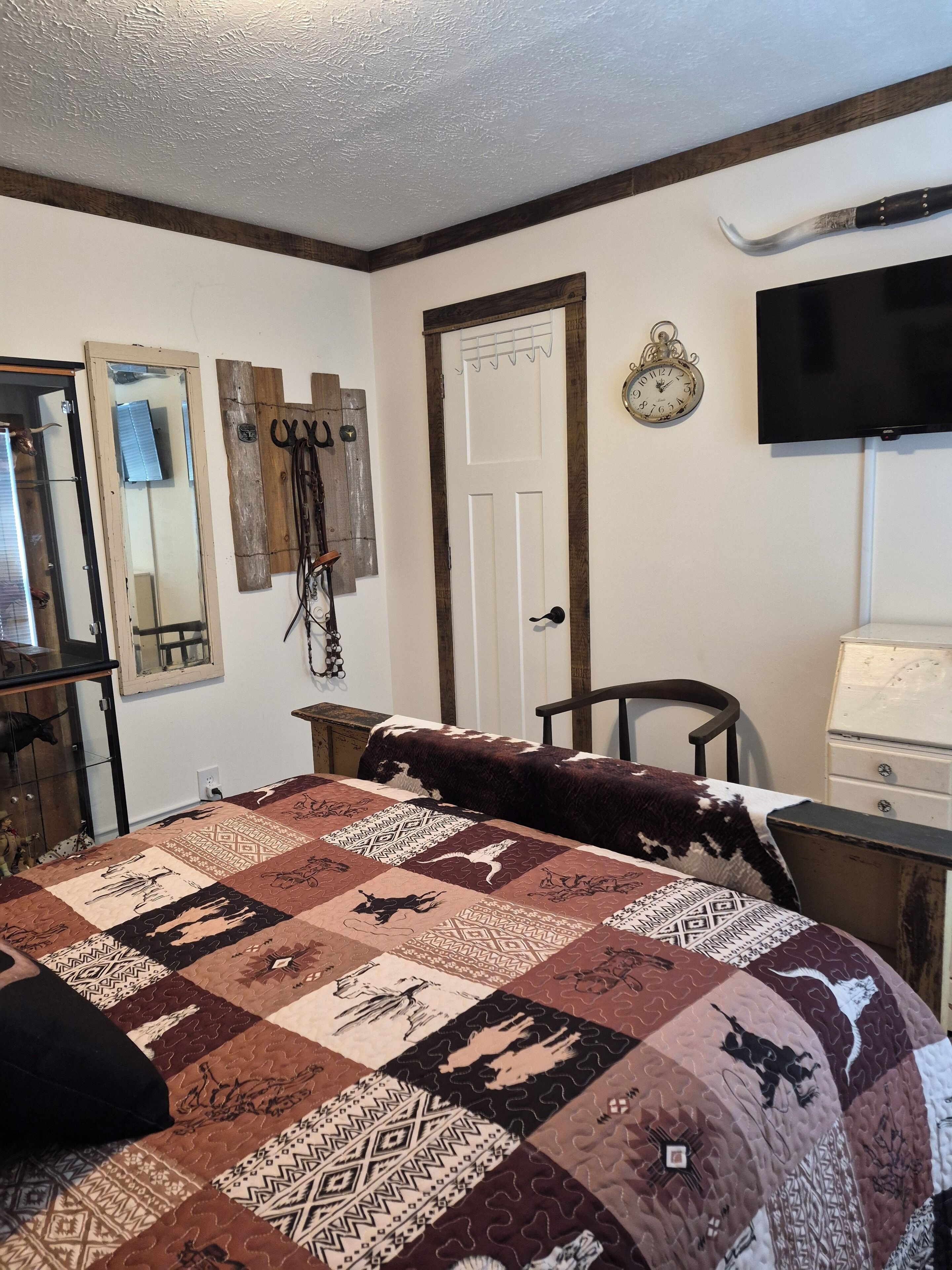 Un dormitorio con una cama grande, cabecera de madera, televisor, reloj y espejo.