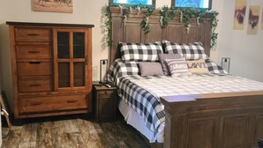 A bedroom with a wooden bed, a wooden dresser, and a window with a view.