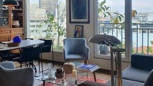 Ein modernes Wohnzimmer mit Essbereich, großen Fenstern und Blick auf die Stadt.