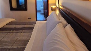 Ein Hotelzimmer mit einem Bett, einem Nachttisch, einem Spiegel und einem gerahmten Bild an der Wand.