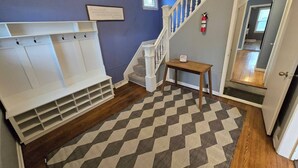 Ein Flur mit einer Holzbänklern, einer Treppe und einem Teppich.