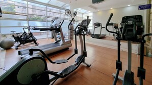 A gym with various exercise equipment, large windows, and a sign indicating resident parking.