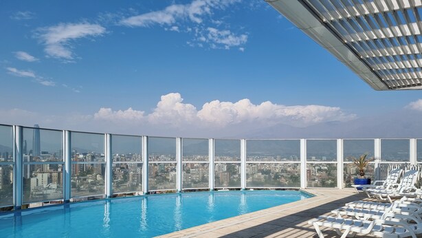 A rooftop pool with clear views of a cityscape and mountains.