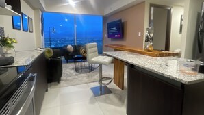 A modern kitchen with a bar area, a dining space with a view, and a large window.