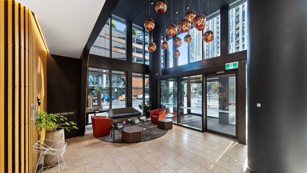 A spacious lobby with a high ceiling, large windows, and modern furniture. - Docklands Melbourne CBD Views (Docklands)