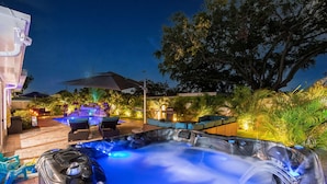 A hot tub with a waterfall feature, surrounded by outdoor furniture and a pool. - Stunning 3 BR Oasis with Waterfall Grotto by white sands of Clearwater Beach (Clearwater)