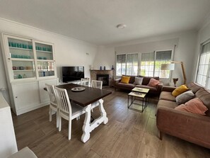 A living room with a dining table, sofas, and a fireplace.