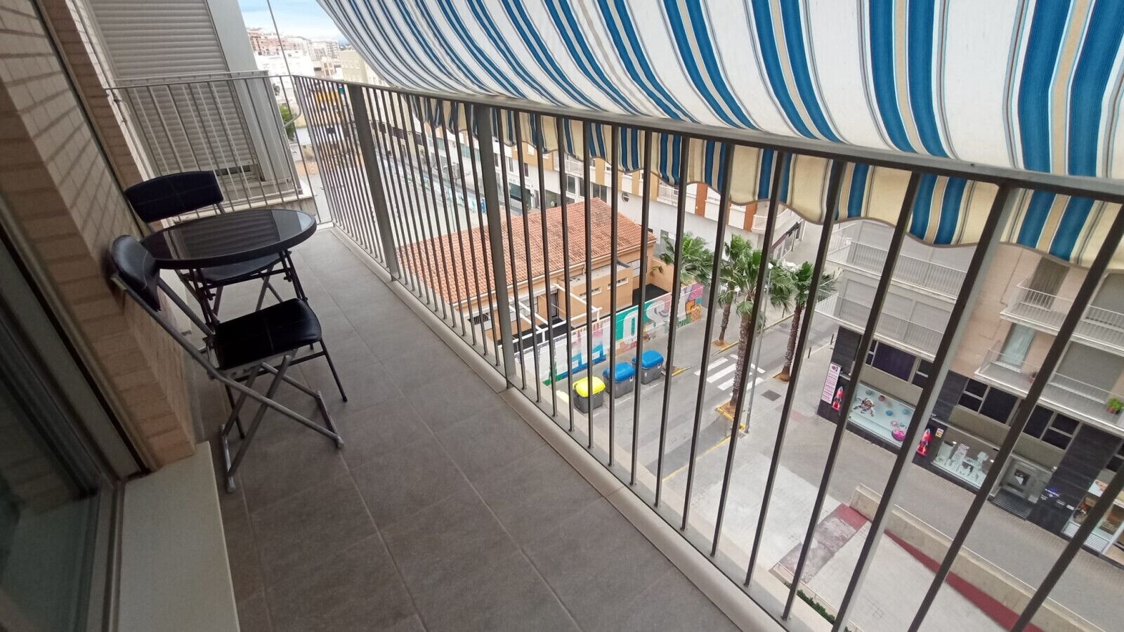 Un balcone con vista sulla strada, un tavolino e due sedie.