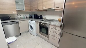 Eine moderne Küche mit Edelstahlgeräten, einer eingebauten Waschmaschine und einer Arbeitsplatte aus Granit.