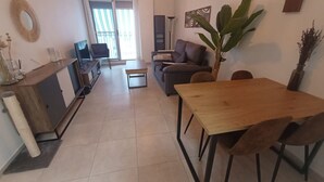 Ein modernes Wohnzimmer mit einem Holzespeisetisch und Stühlen, einem Sofa und einer großen Pflanze.