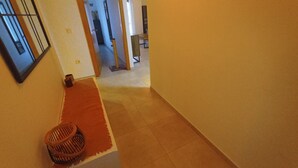 Ein Flur mit Holzboden, einem roten Teppich und einem Korbwäscheschrank.