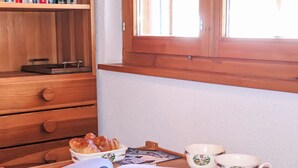 A wooden desk with a book, a bowl of croissants, and two cups with floral designs.