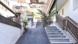 A narrow alleyway leading up a set of stone steps to a building with a wooden fence.