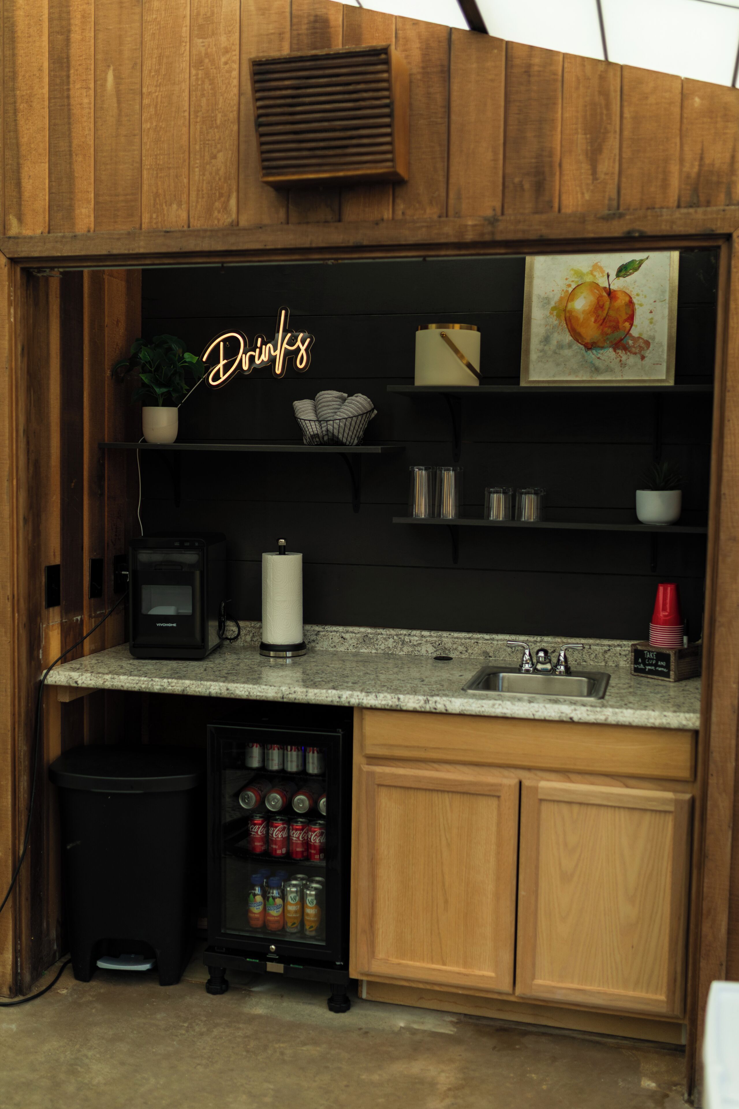 Un área de cocina compacta con encimera, lavamanos y refrigerador para bebidas.