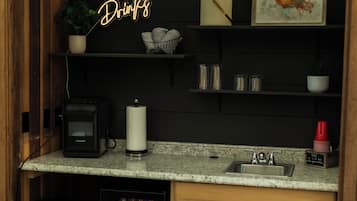 Un área de cocina compacta con encimera, lavamanos y refrigerador para bebidas.