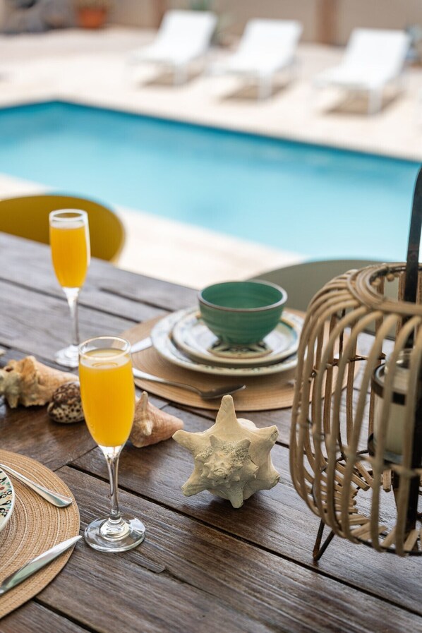 A wooden table with two glasses of orange juice, a green bowl, and a starfish decoration.