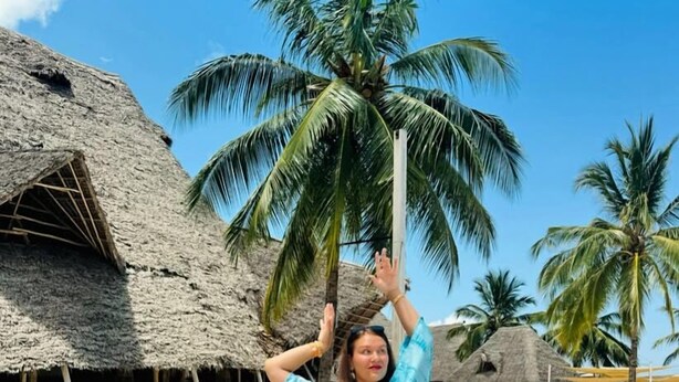 Eine Strandlounge mit strohgedeckten Hütten, Palmen und Holzliegen.