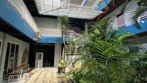 A multi-level atrium with a central open space, surrounded by potted plants and benches. - Grand Mahoni Hotel (Banda Aceh)